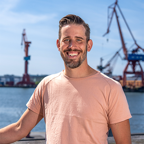 Tobias Rosén som står vid kajkanten vid stenpiren. I Bakgrunden syns Göteborgskranarna. Tobias ler stort.